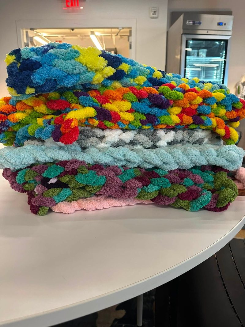 Stack of colorful handmade blankets on a table
