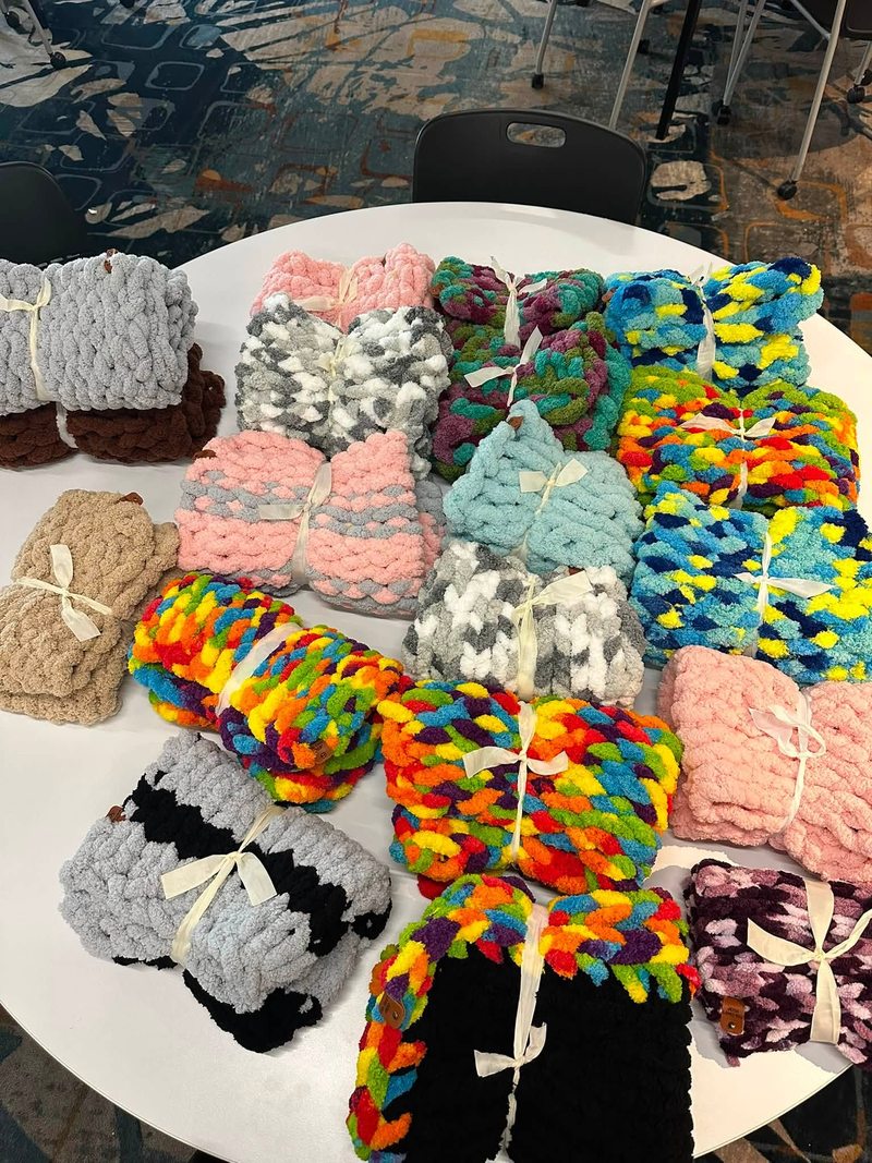 Handmade blankets in many colors arranged across a round table